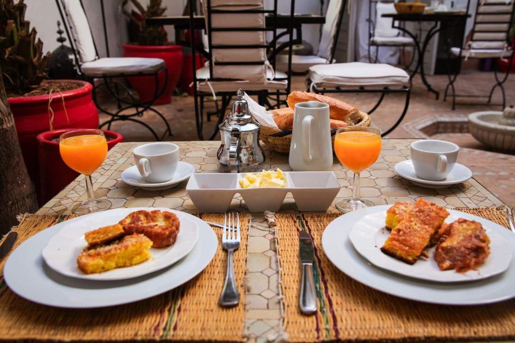 una mesa con platos de comida y vasos de zumo de naranja en Dar Nabila, en Marrakech