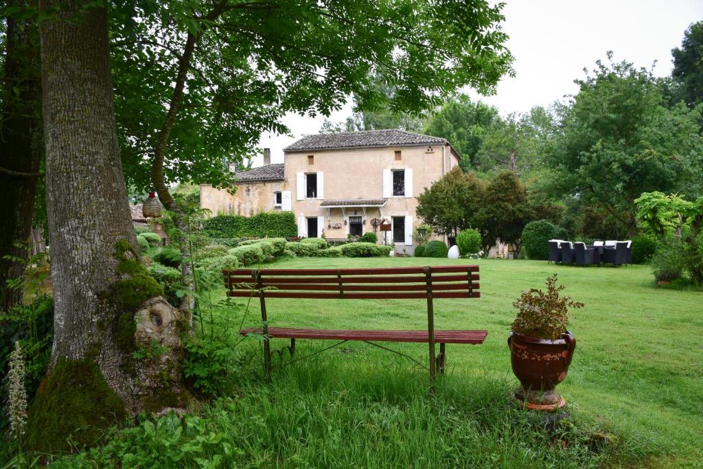 a bench sitting in the grass in front of a house at Moulin De Ladausse in Monflanquin