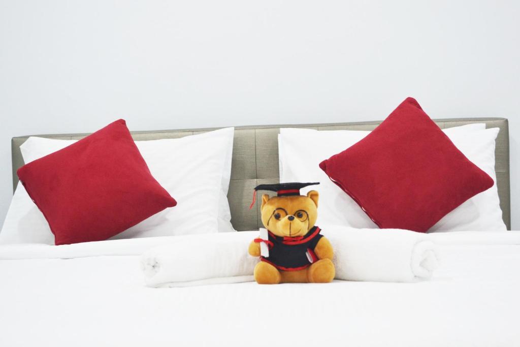 een teddybeer met een afstudeerhoed op een bed bij Holidays Vacation Suite in Bentong