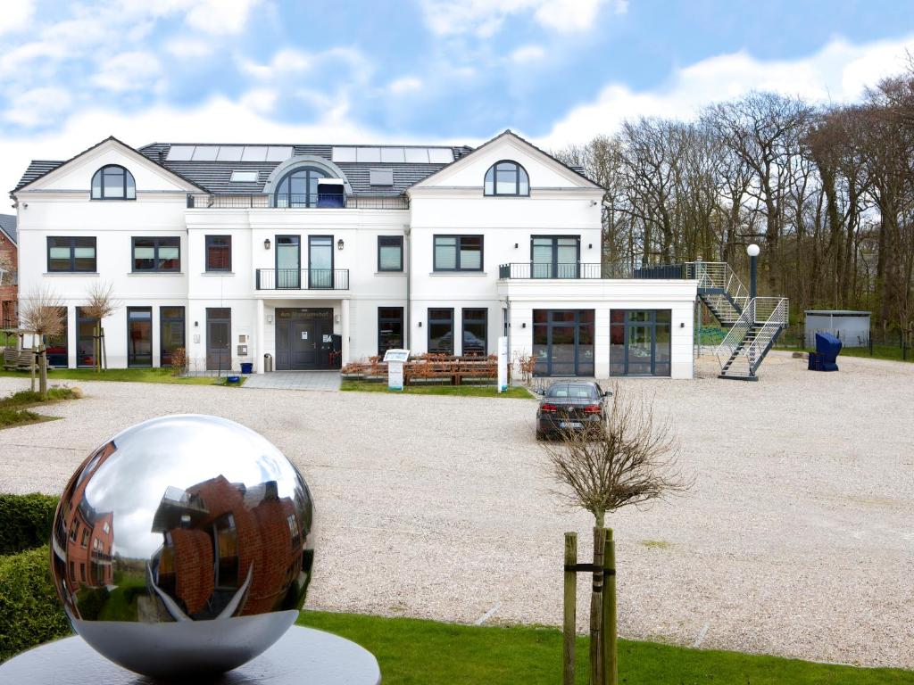 a large white house with a silver ball in front of it at Aparthotel Museumshof in Fehmarn
