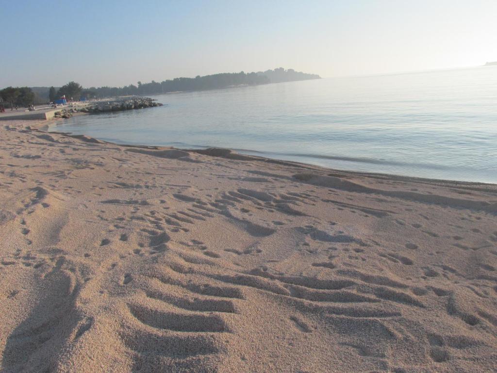 a beach with footprints in the sand next to the water at Apartment Carmen in Pula