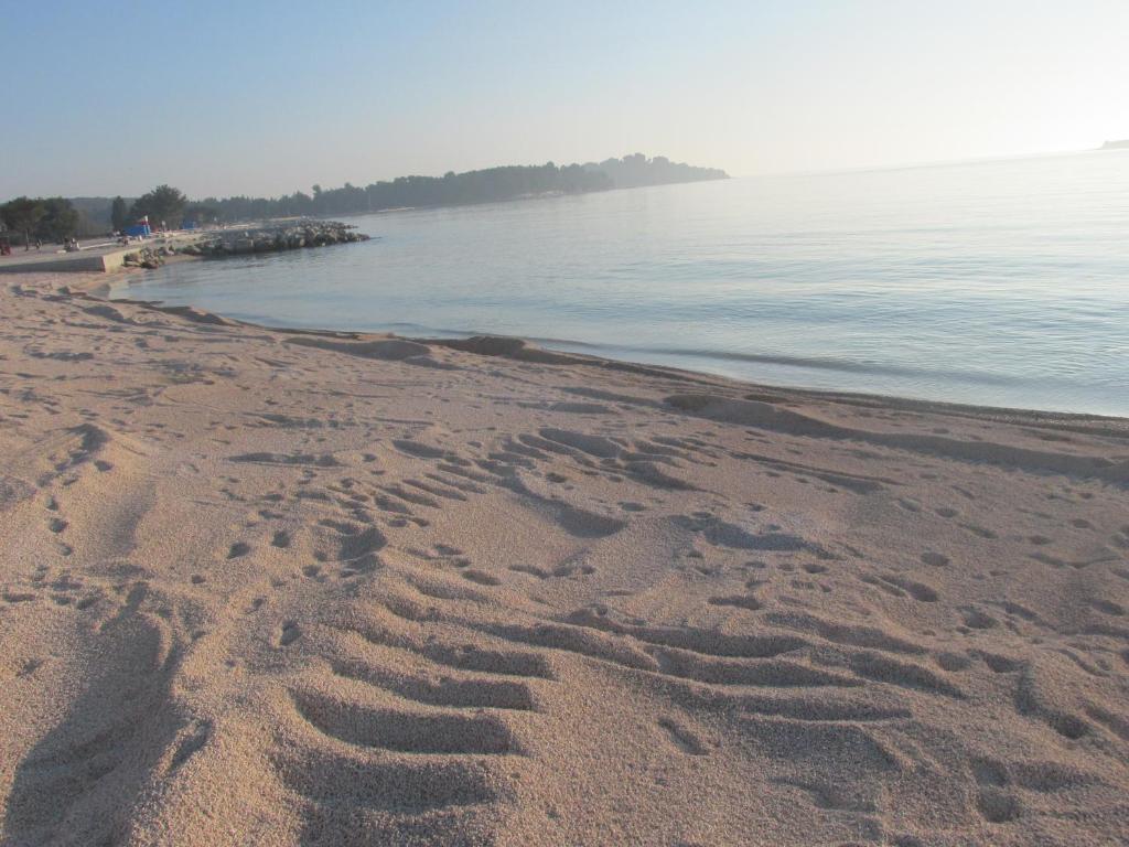 une plage avec des empreintes de pieds dans le sable à côté de l'eau dans l'établissement Apartment Carmen, à Pula