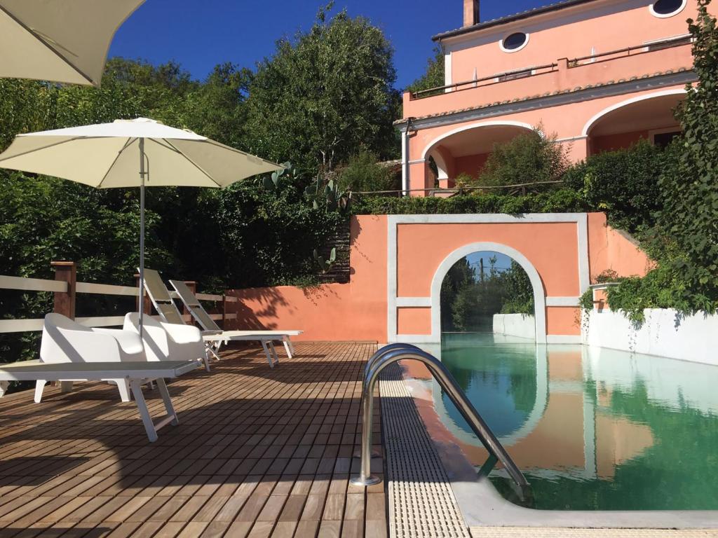 a pool with an umbrella and chairs next to a building at La Vecchia Quercia in San Cipriano Picentino