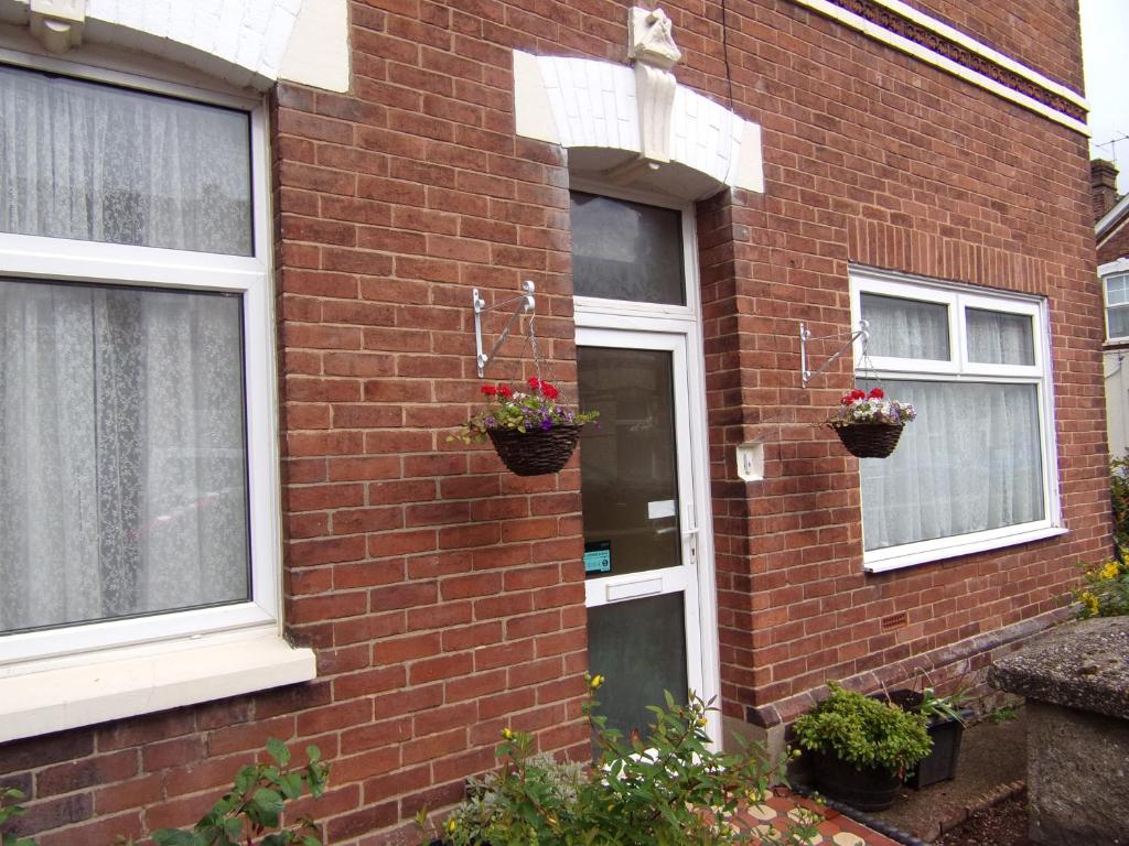 a brick house with two windows and two potted plants at St Anne's Road Guest House in Exeter
