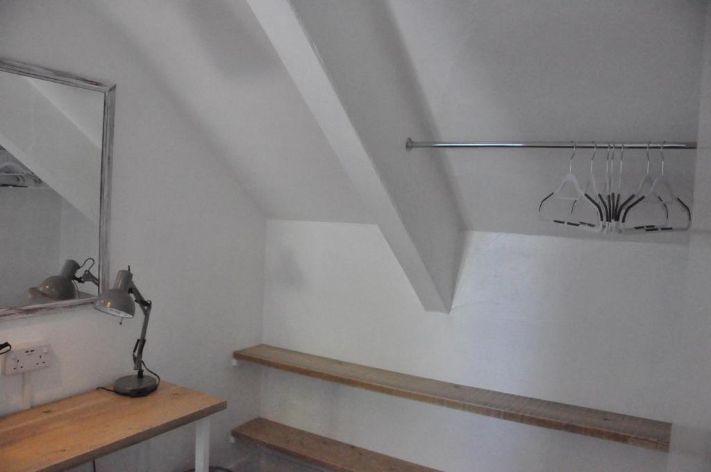 um quarto branco com uma escada e um espelho em Gordon House B & B em Tintagel