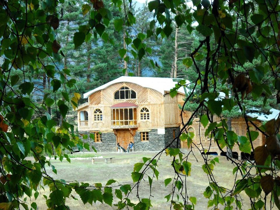 a large wooden building in the middle of a field at Hotel Tusheti in Omalo