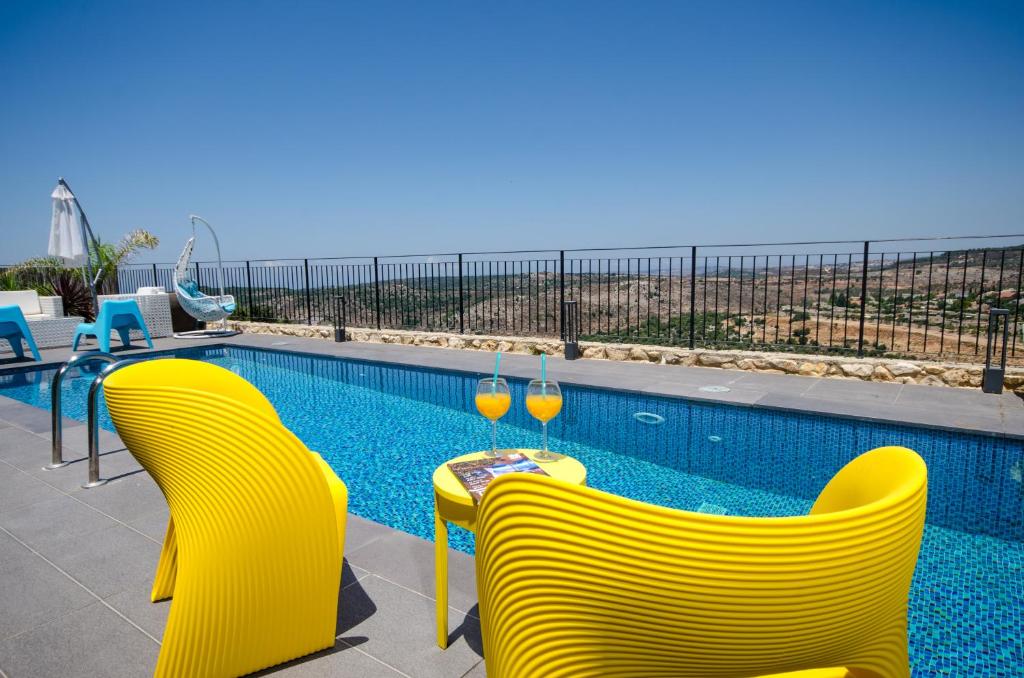 dos copas de vino sentadas en una mesa junto a una piscina en The Fifties suites, en Kefar Weradim
