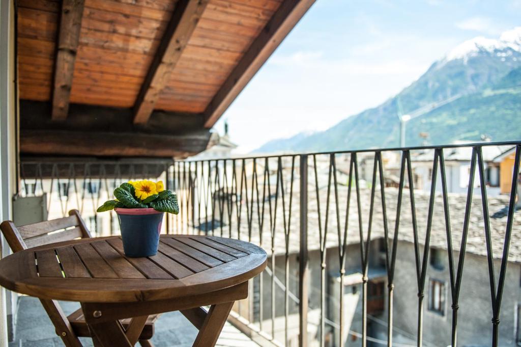 a wooden table with a flower pot on a balcony at Maison Forum in Aosta