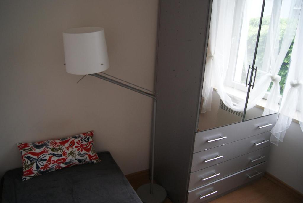 a bedroom with a dresser and a lamp and a pillow at Apartamenty Oliwa in Gdańsk