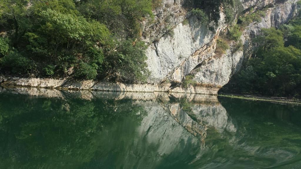 a body of water next to a mountain with trees at Restaurant &amp; rooms Visovac - best value in Skradin