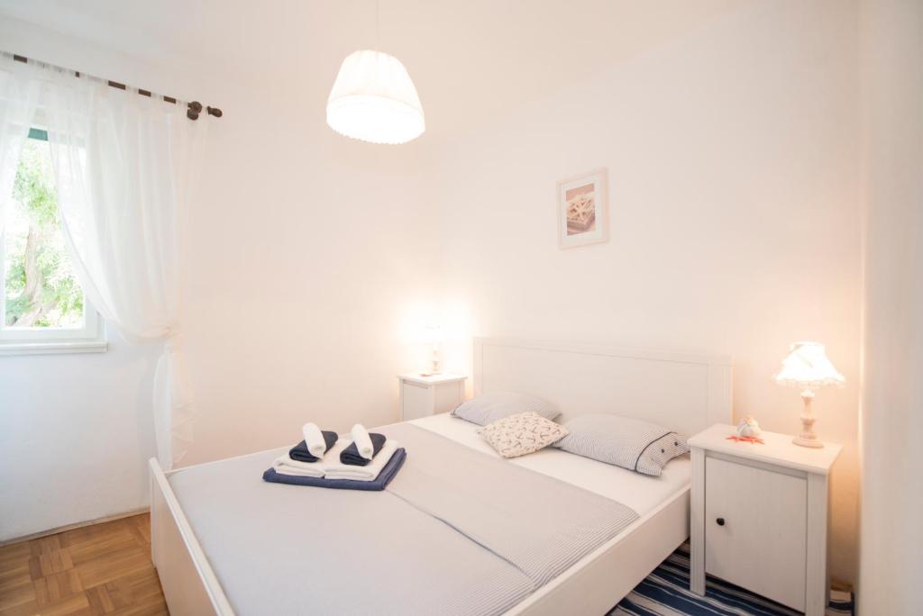 a white bedroom with a bed with shoes on it at Maritimo Apartment in Split