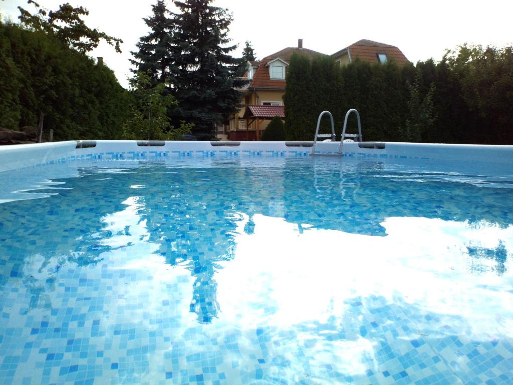 a swimming pool with blue tiles on the water at Anikó Apartmanház in Balatonföldvár