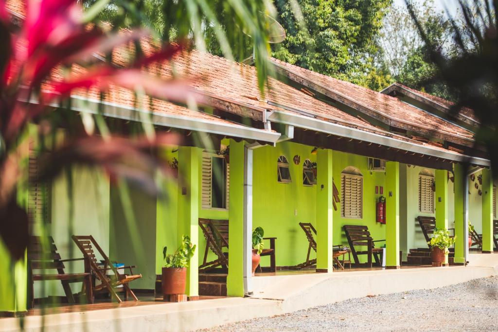 een groen gebouw met stoelen en tafels ervoor bij Pousada do Peralta in Bonito