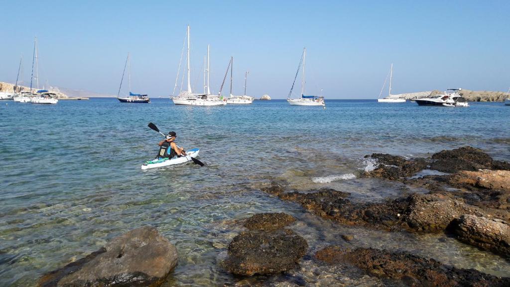 a person in a kayak in the water with boats at Vrahos Boutique Hotel in Karavostasi