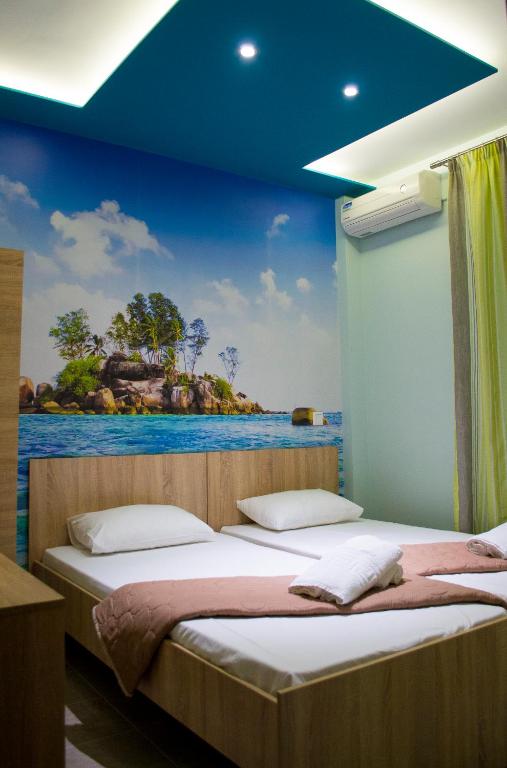 dwa łóżka w pokoju z obrazem na ścianie w obiekcie Milonas House Apartments w mieście Paralia Dionisiou