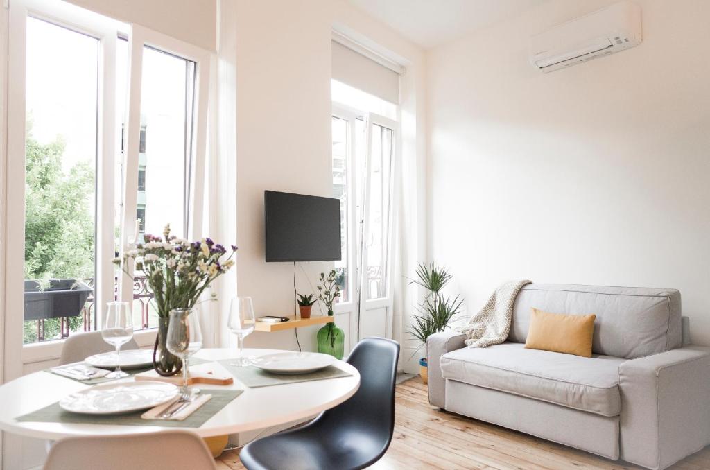 een witte woonkamer met een tafel en een bank bij Zelije Apartments Trindade in Porto