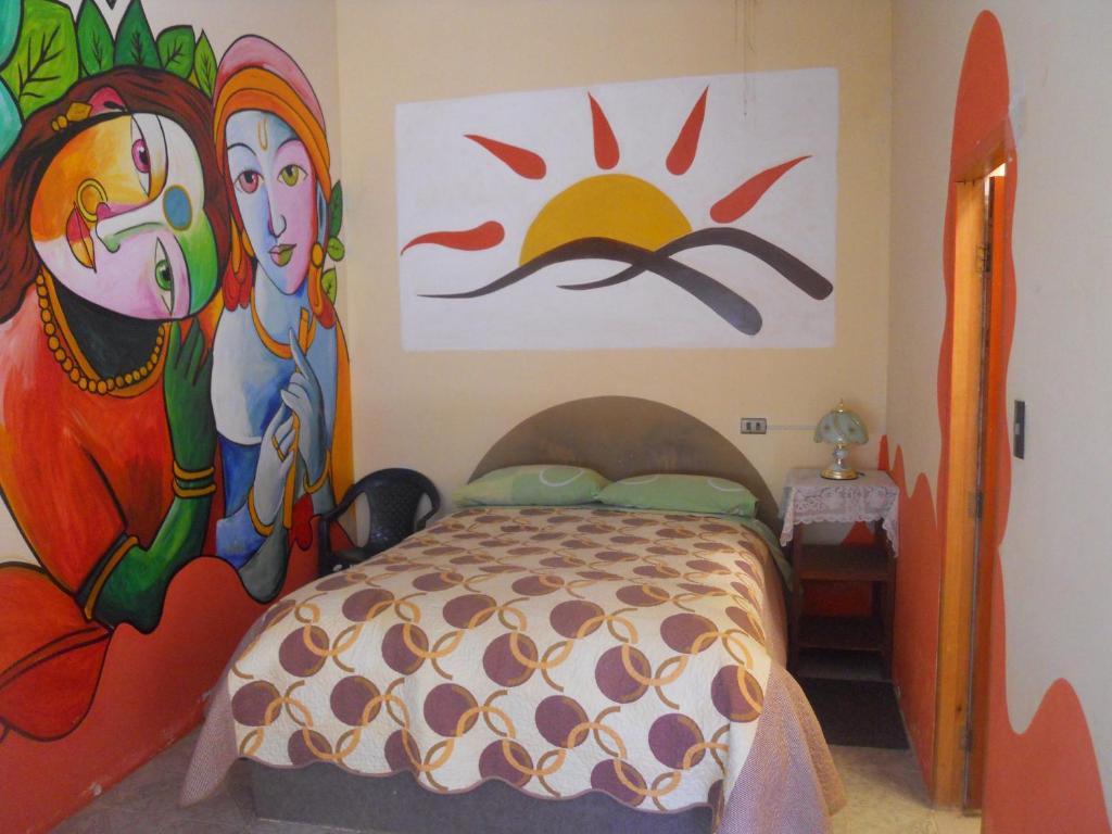 a bedroom with a bed with paintings on the wall at Hostal La Casa del Sol in Copacabana