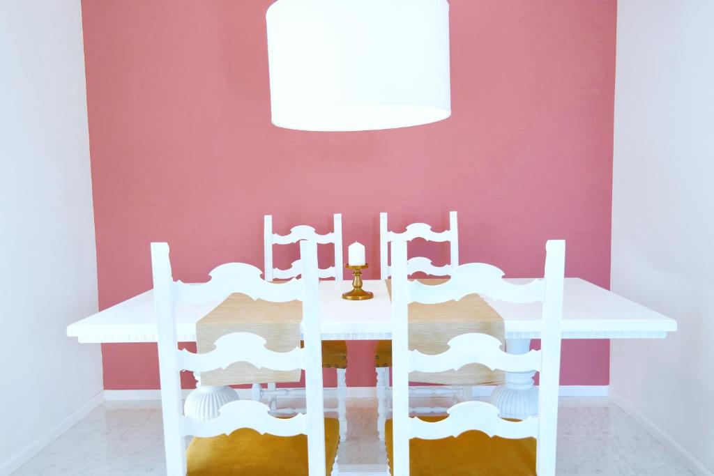 a white table and chairs in a room with a pink wall at Villa Alba in Acitrezza