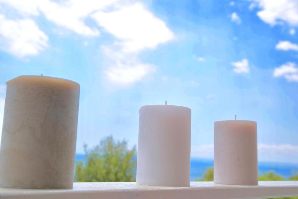 three white candles sitting on a window sill at Villa Alba in Acitrezza