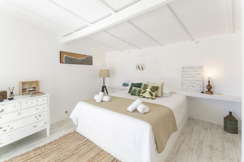 a white bedroom with a bed and a dresser at O Moinho da Roca in Azoia
