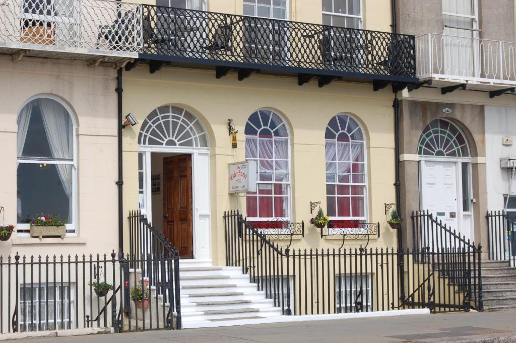 a yellow house with stairs and a balcony at The Edenhurst Guesthouse in Weymouth