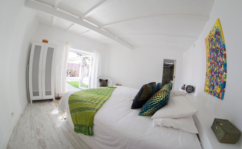 a white bedroom with a large white bed with pillows at O Moinho da Roca in Azoia