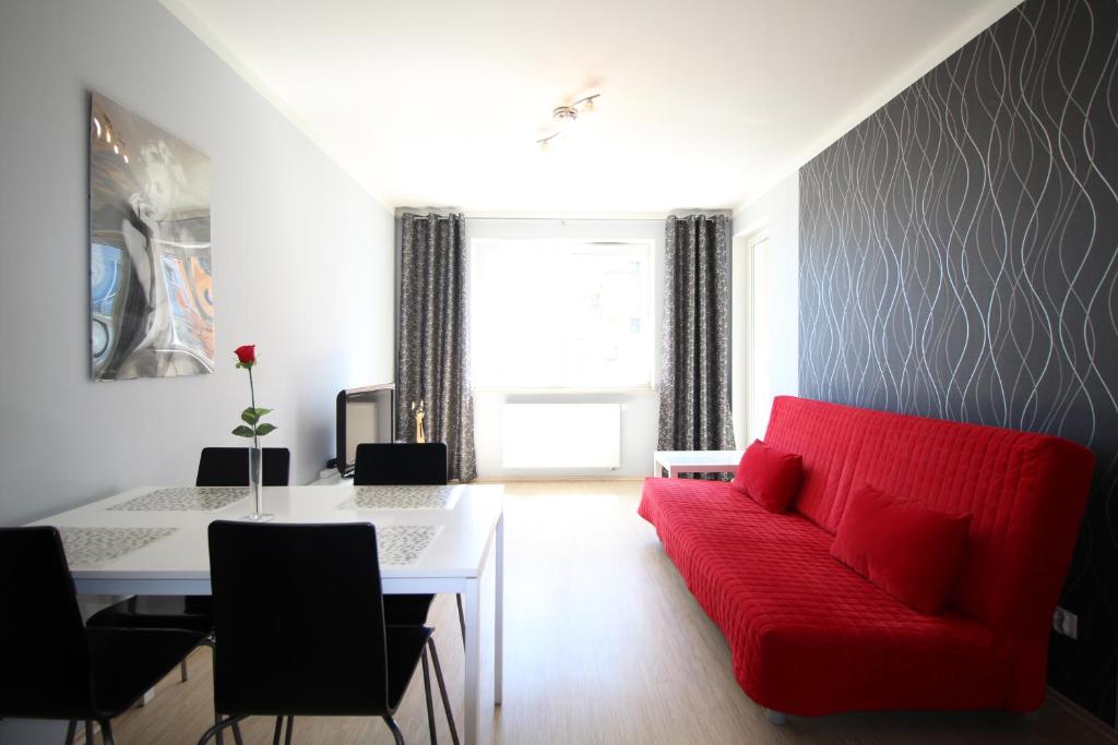 a living room with a red couch and a table at Sea Apartment in Gdańsk