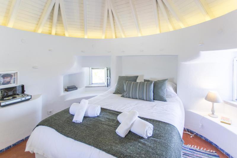 a bedroom with a large white bed with two white towels on it at O Moinho da Roca in Azoia