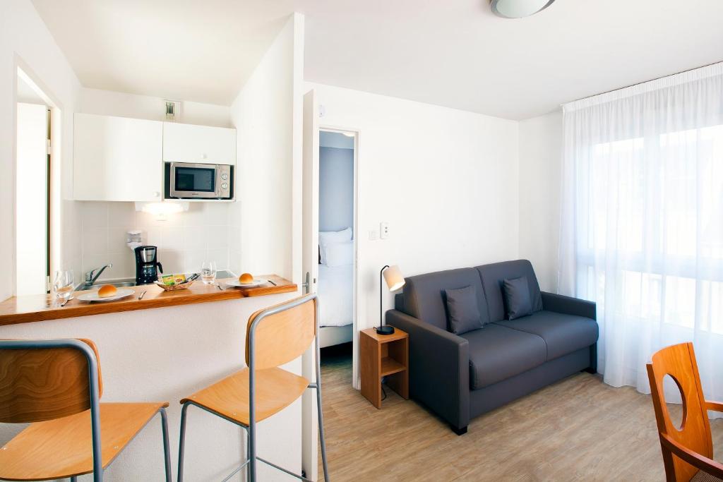 eine Küche und ein Wohnzimmer mit einem Sofa in der Unterkunft Séjours & Affaires Angers Atrium in Angers
