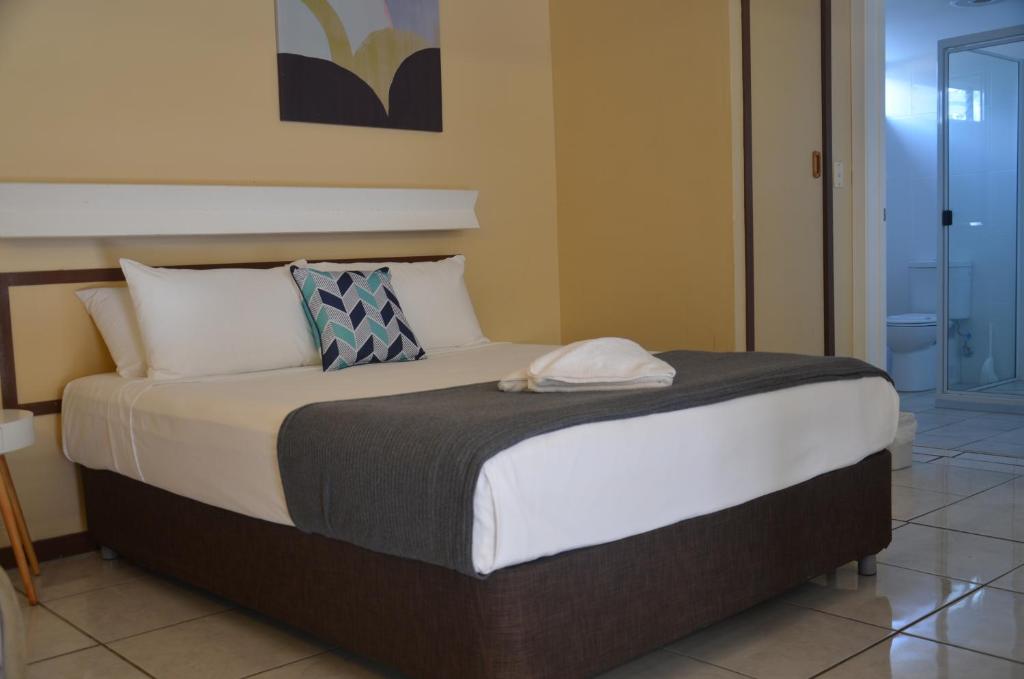 
a large bed with a white bedspread and pillows at Ambassador Motel in Rockhampton
