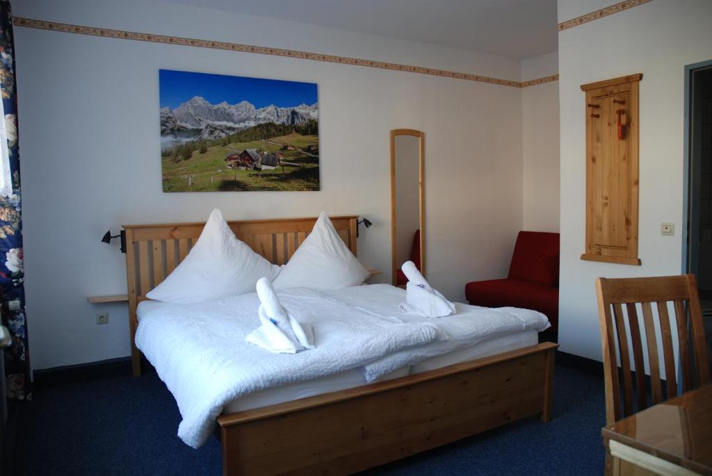Schlafzimmer mit einem Bett mit weißer Bettwäsche und einem roten Stuhl in der Unterkunft Hotel Stangl in Hamm
