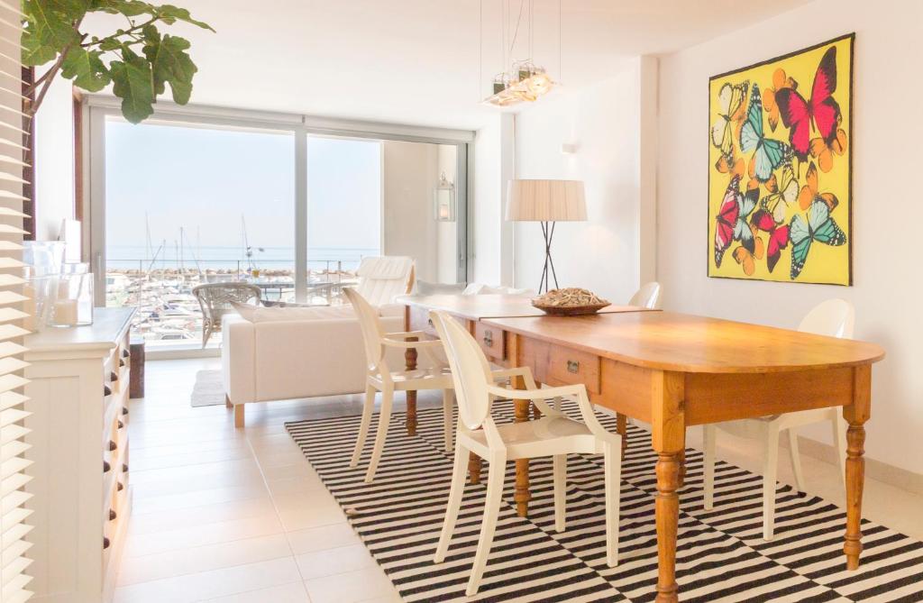 comedor con mesa de madera y sillas blancas en Casa Catalina Mallorca Sea Front, en Can Picafort