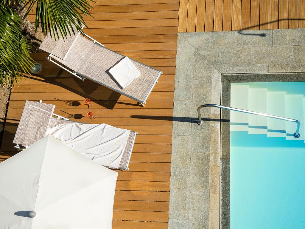 a swimming pool with chairs and a lamp on a building at Jardis Boutique Garni Hotel in Lana