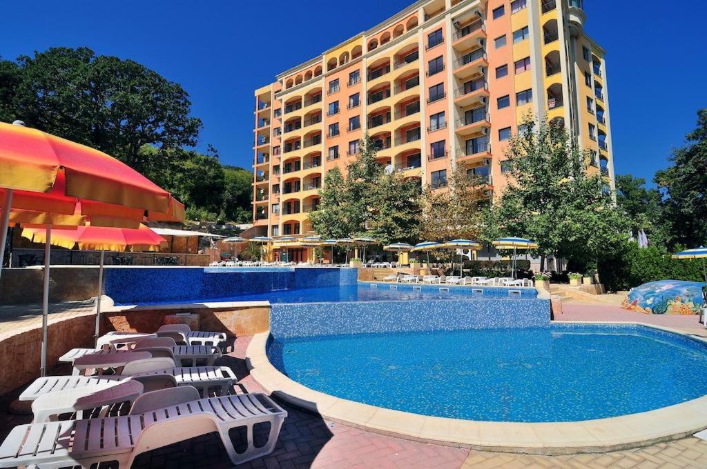 a hotel with a pool and chairs and a building at Kris Apartments at Paradise Green Park in Golden Sands