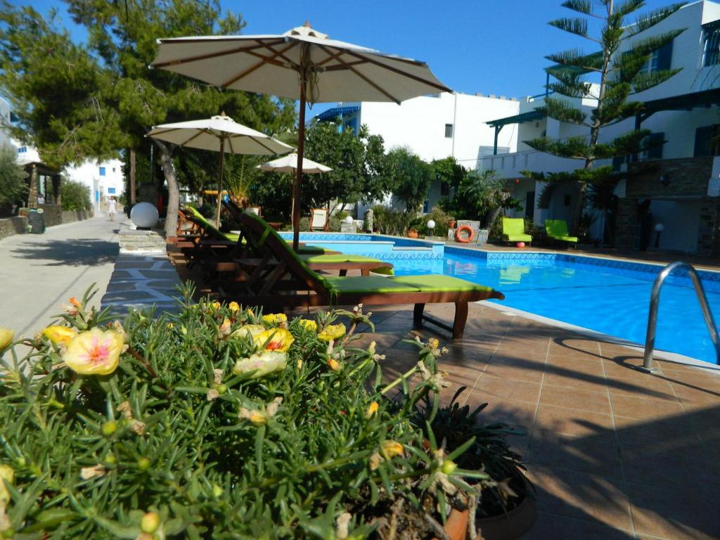 una piscina con due sedie e un ombrellone e alcune piante di Ioanna Apartments ad Agios Prokopios
