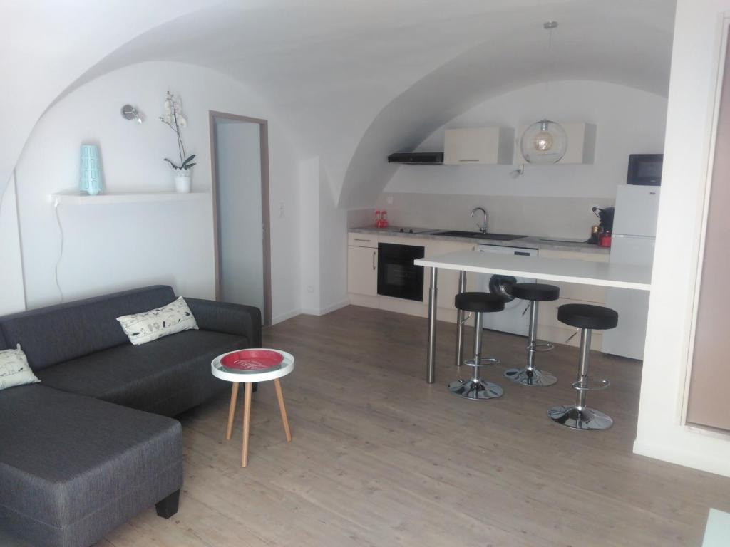 een woonkamer met een bank en een tafel en een keuken bij Gite du MISTRAL in Saint-Jean-de-Fos