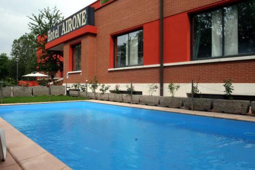 a blue swimming pool in front of a building at Airone Hotel in Reggio Emilia