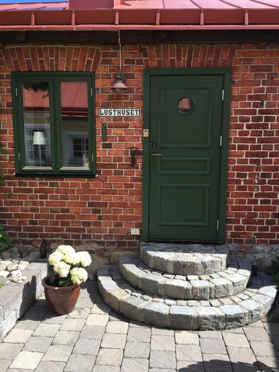 eine grüne Tür und eine Treppe vor einem Backsteingebäude in der Unterkunft Lusthuset in Sölvesborg