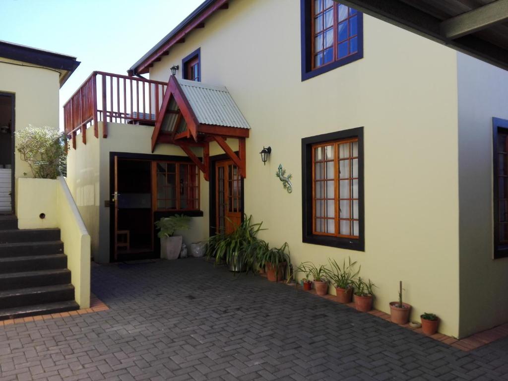 una casa bianca con cortile con piante in vaso di The Olde House a Port Elizabeth