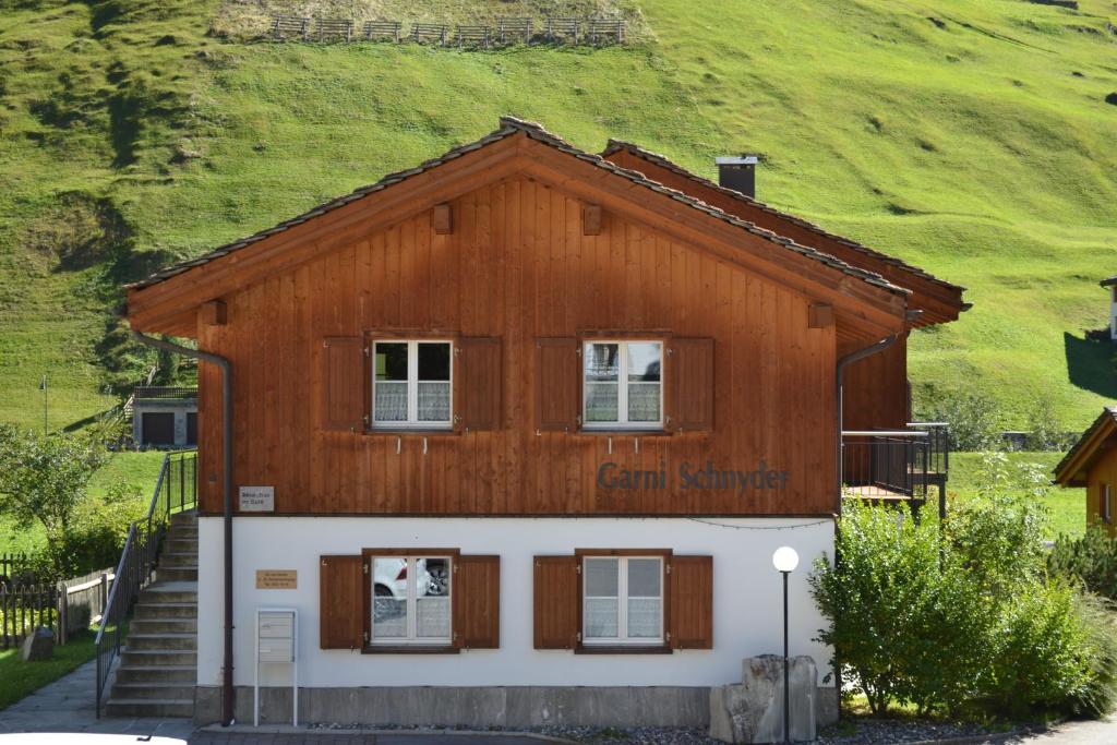 uma pequena casa com uma colina verde ao fundo em Schnider Bed&Breakfast und Café em Vals