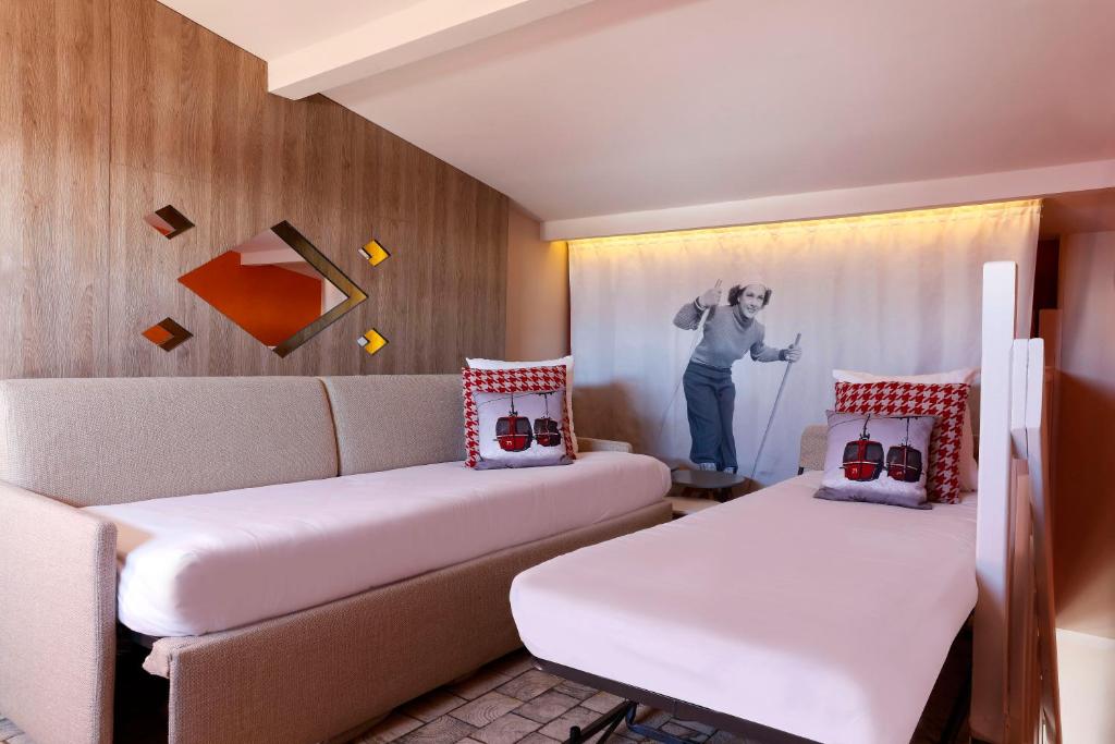 a room with a couch and a person standing in a window at Grandes Rousses Hotel & Spa in L'Alpe-d'Huez