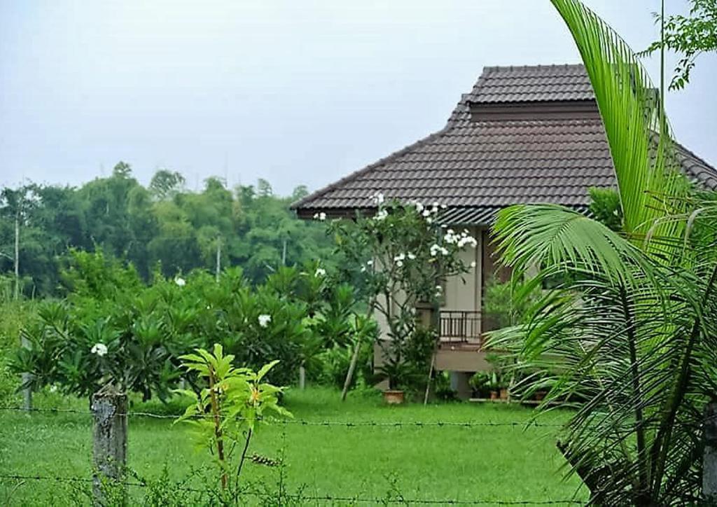 a house with a fence in front of a yard at Jamjuree Garden in Ban Thung Ma Nieo