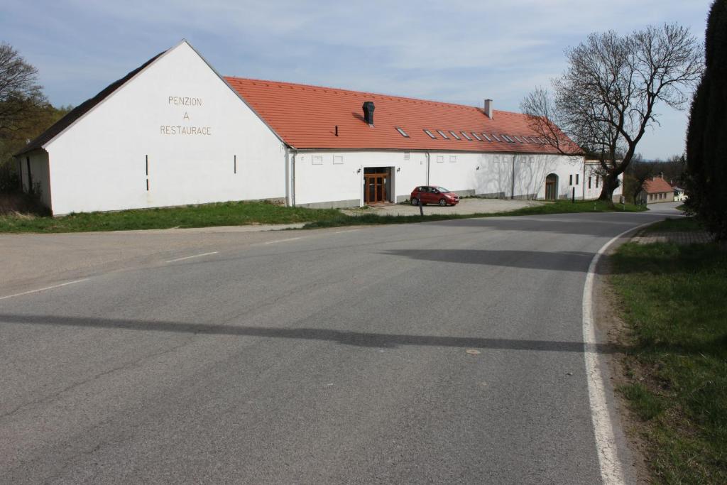 a white barn with a red roof next to a road at Penzion Vanůvecký Dvůr in Telč