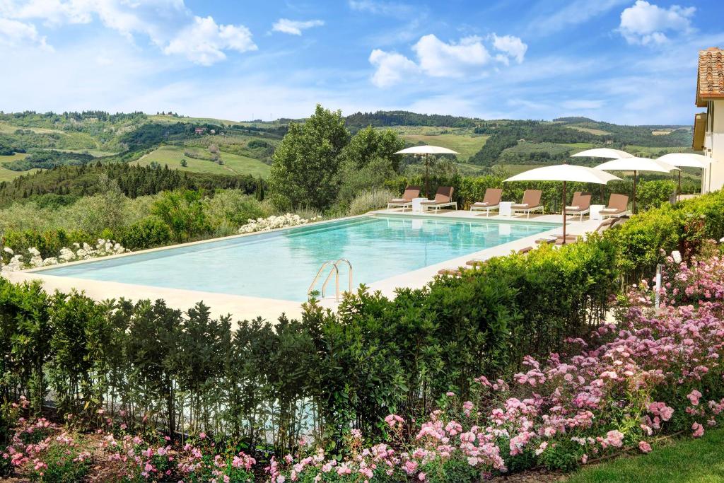 een zwembad met stoelen en parasols in een tuin bij Villa Le Calvane in Montespertoli