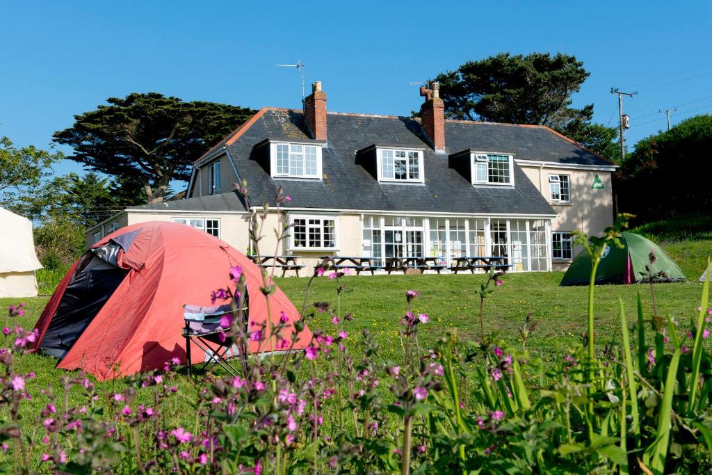 a tent in a field in front of a house at YHA Land's End - Cot Valley in St Just