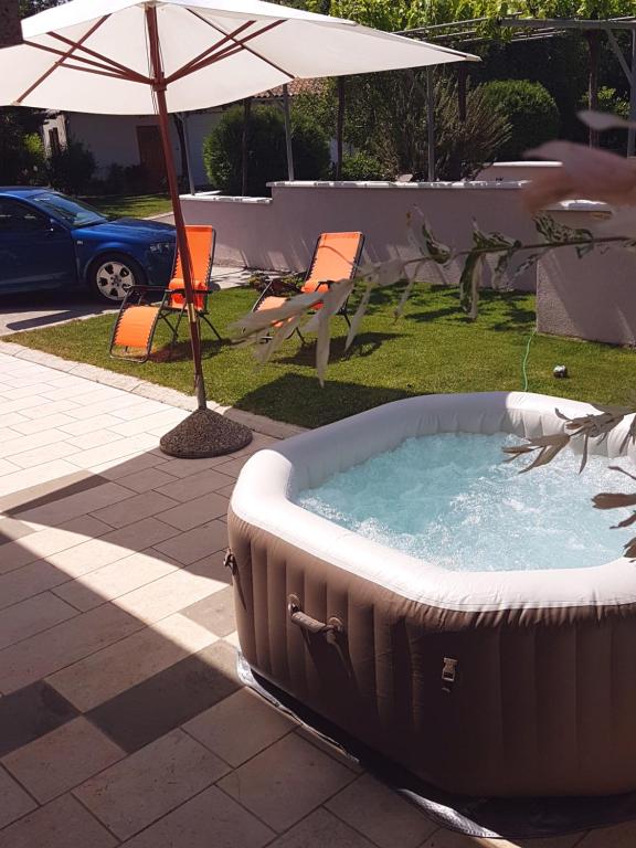 a hot tub in a yard with an umbrella at Apartment Borna in Pazin