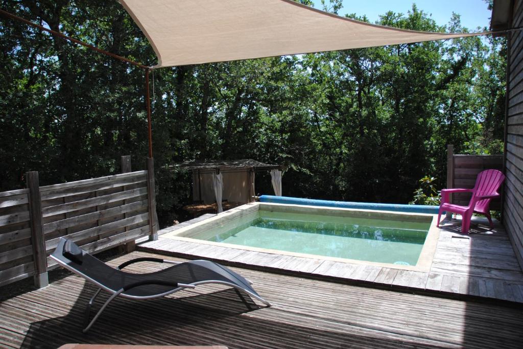 un bain à remous sur une terrasse avec une chaise et un parasol dans l'établissement Insolite Bois Cailloux avec Spa, à Saint-Remèze