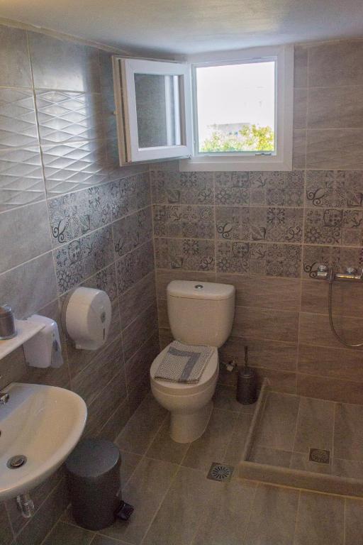 a bathroom with a toilet and a sink and a window at Hotel Antiparos in Antiparos Town