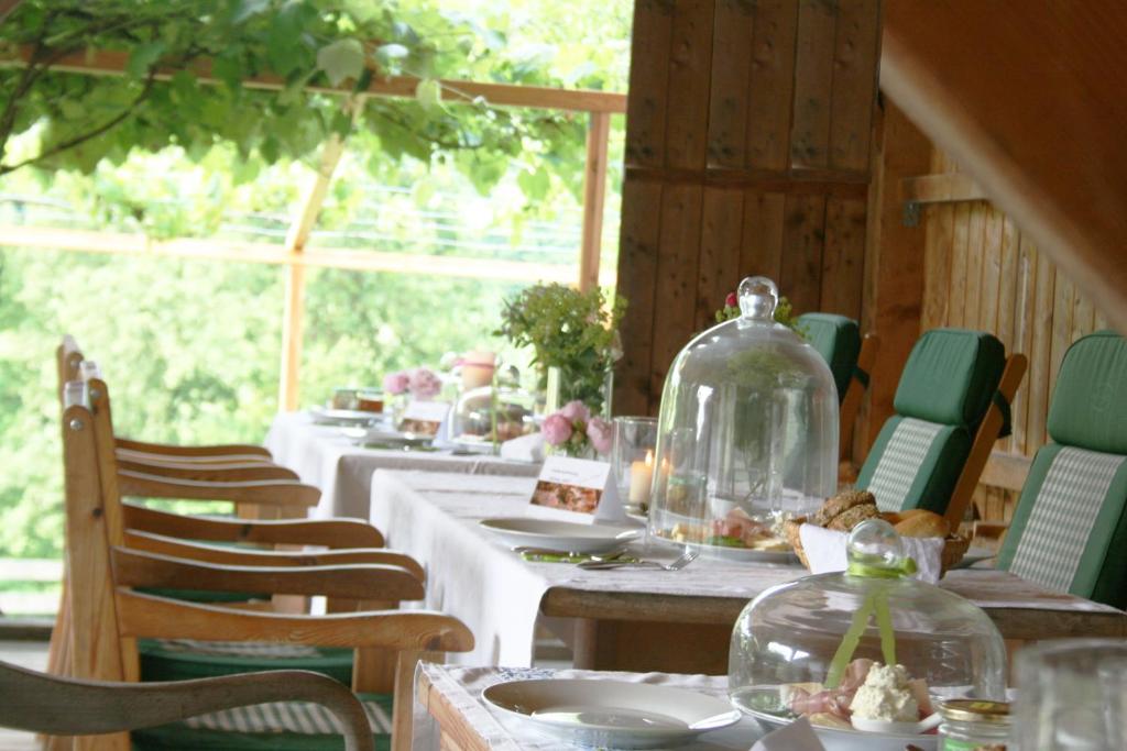 una fila de mesas con placas blancas y jarras de vidrio en Sonnenhaus Grandl en Feldbach