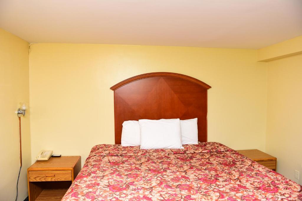 1 dormitorio con 1 cama con cabecero de madera en Royal Inn en Tonawanda